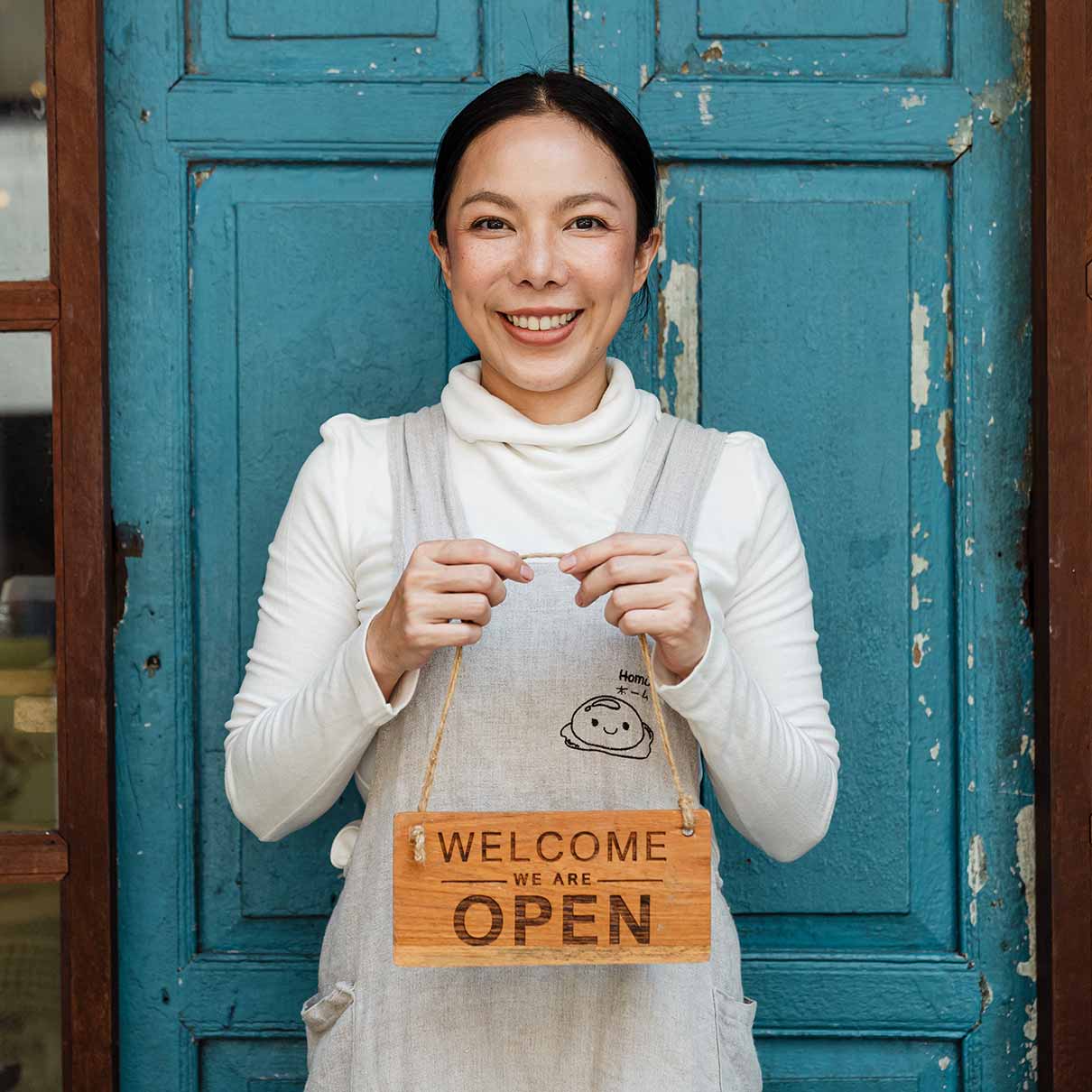 Small Business Owner Happy business owner holding we are open sign in front of a vintage door